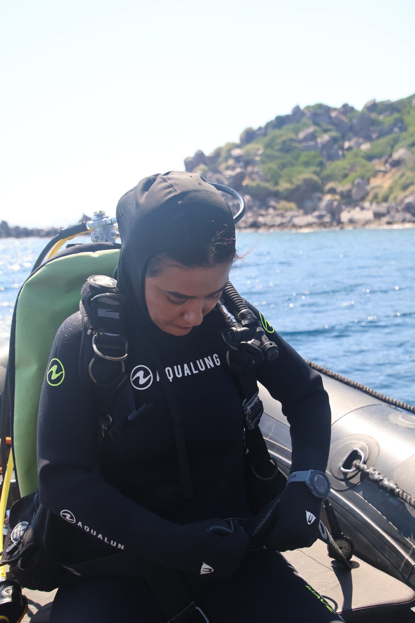 A diver settling into her gear on the RIB tube