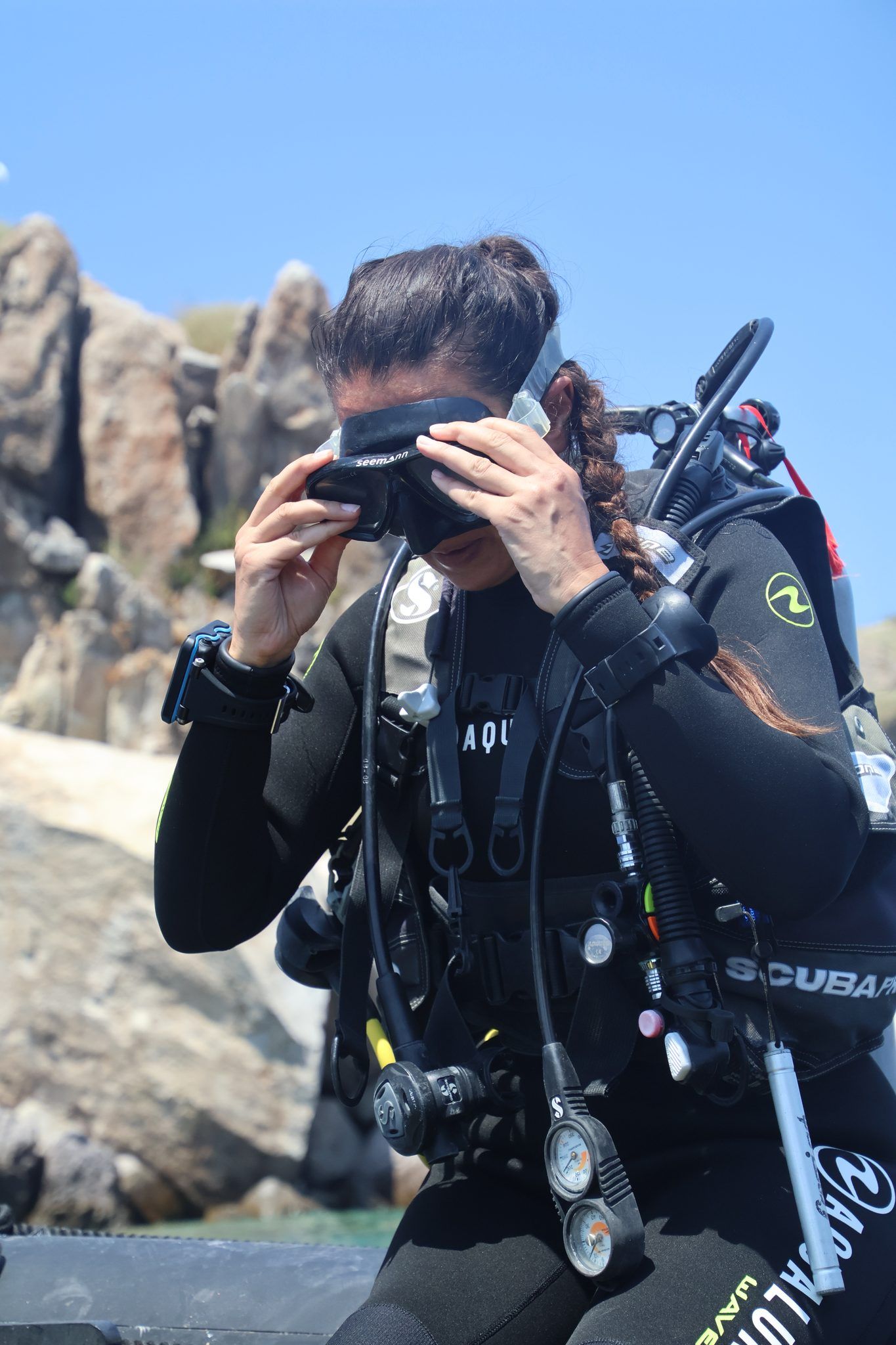 A diver pulling her mask down over her face