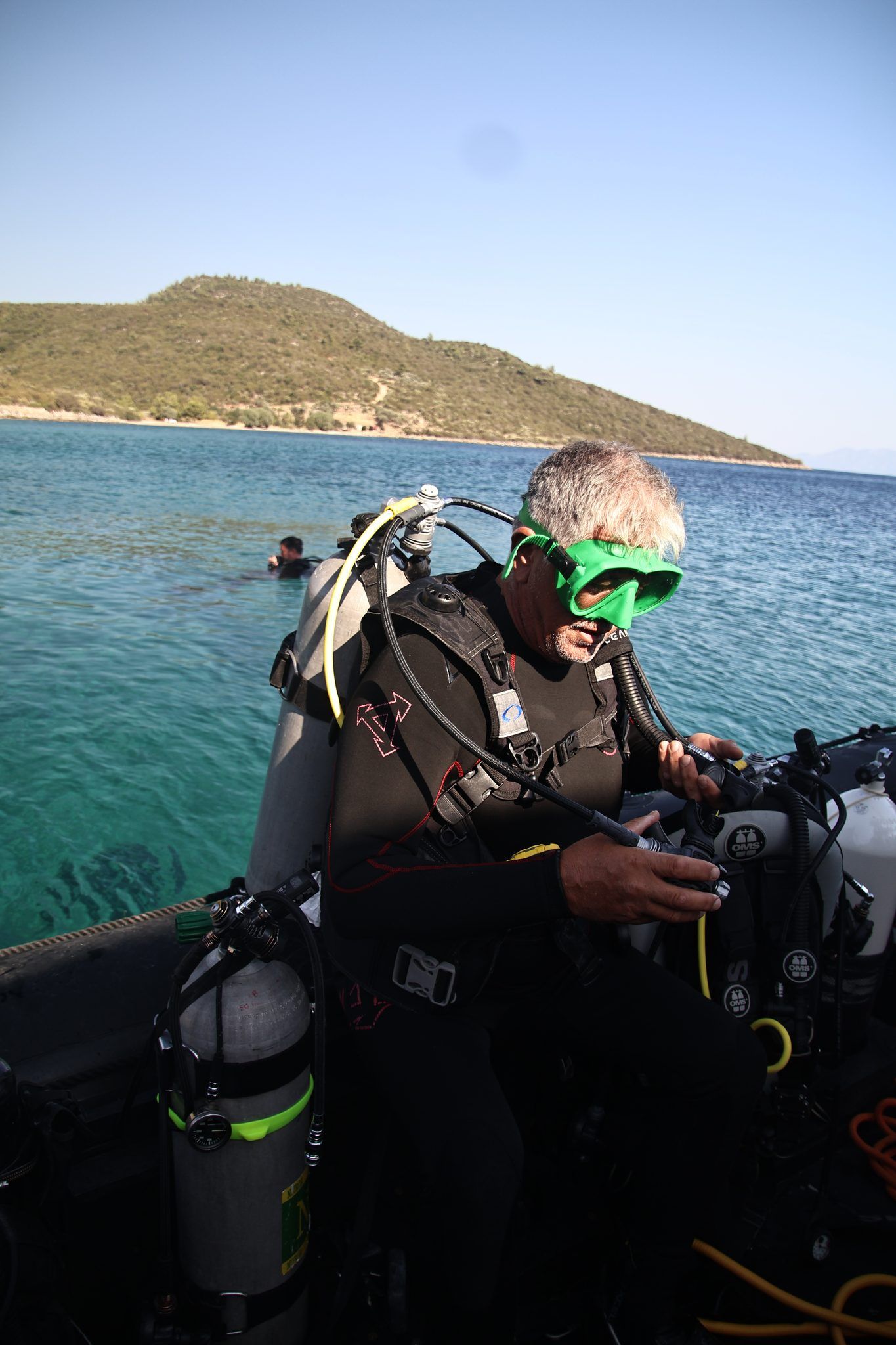 A diver running his gauge check on the RIB, another already in the water behind
