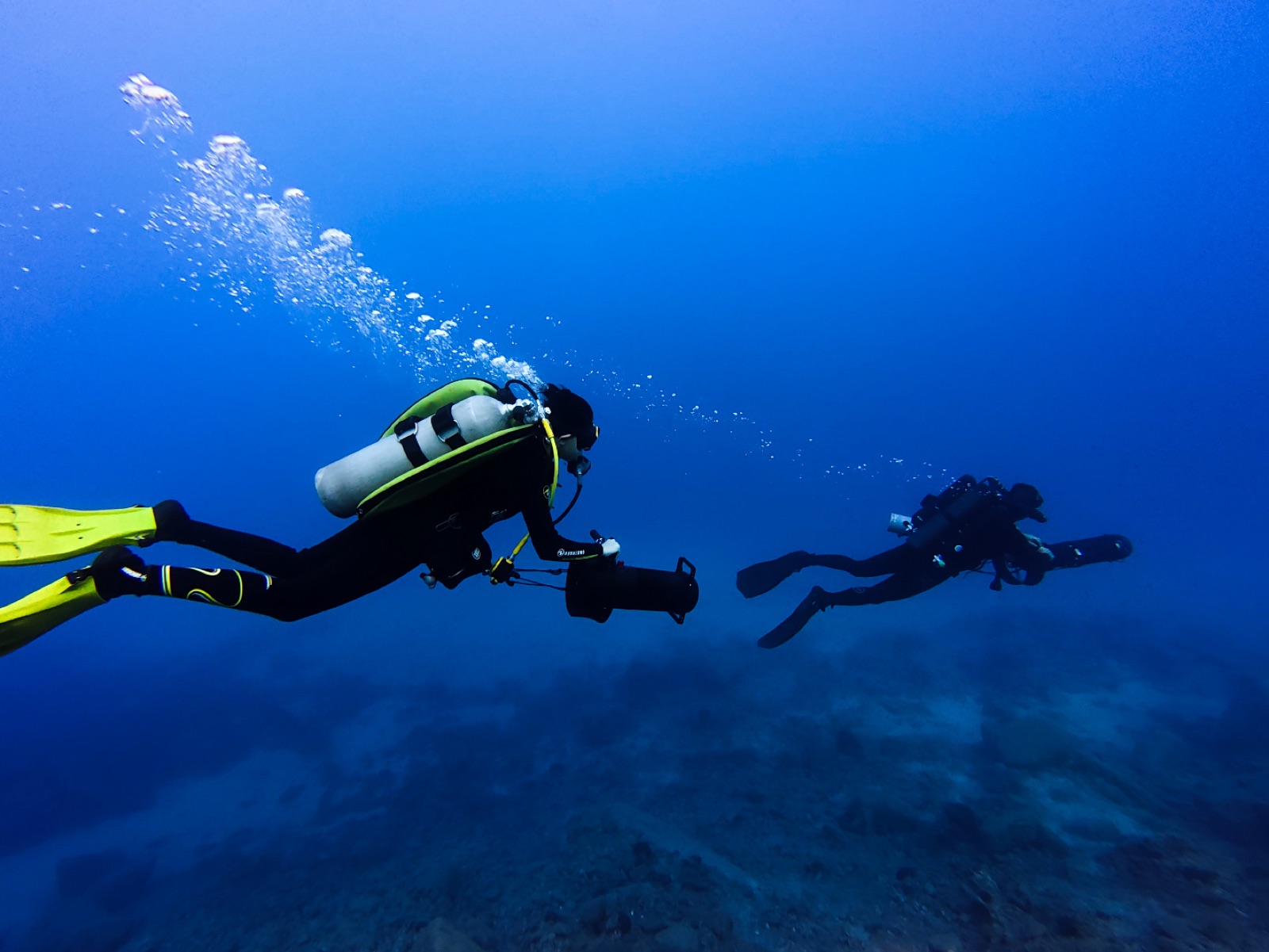 Diver with scooter following a rebreather diver over the reef